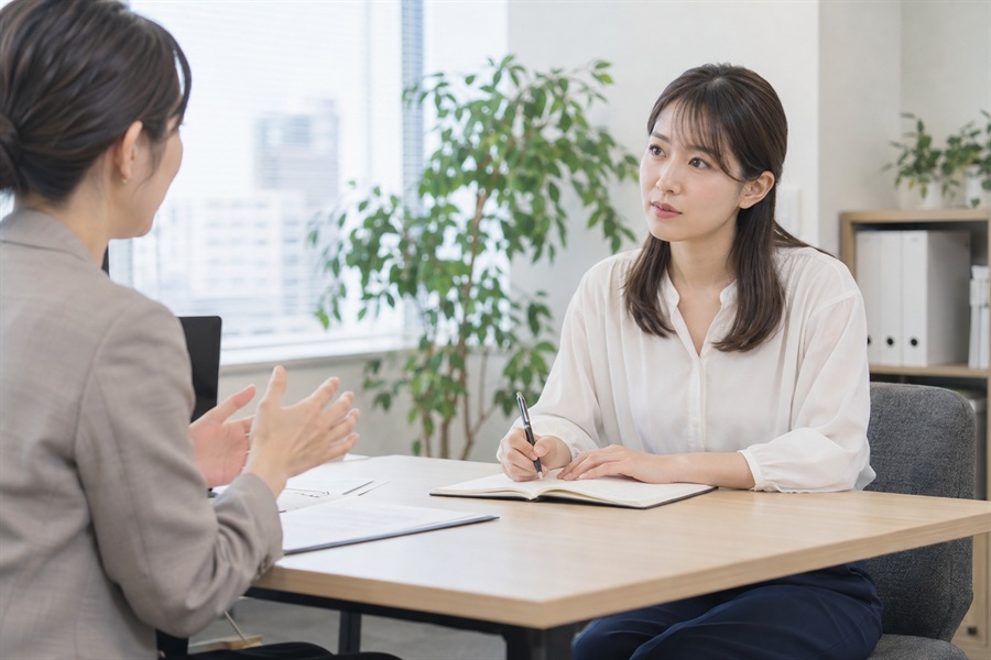 転職エージェントとの面談でメモを取る20代後半の女性